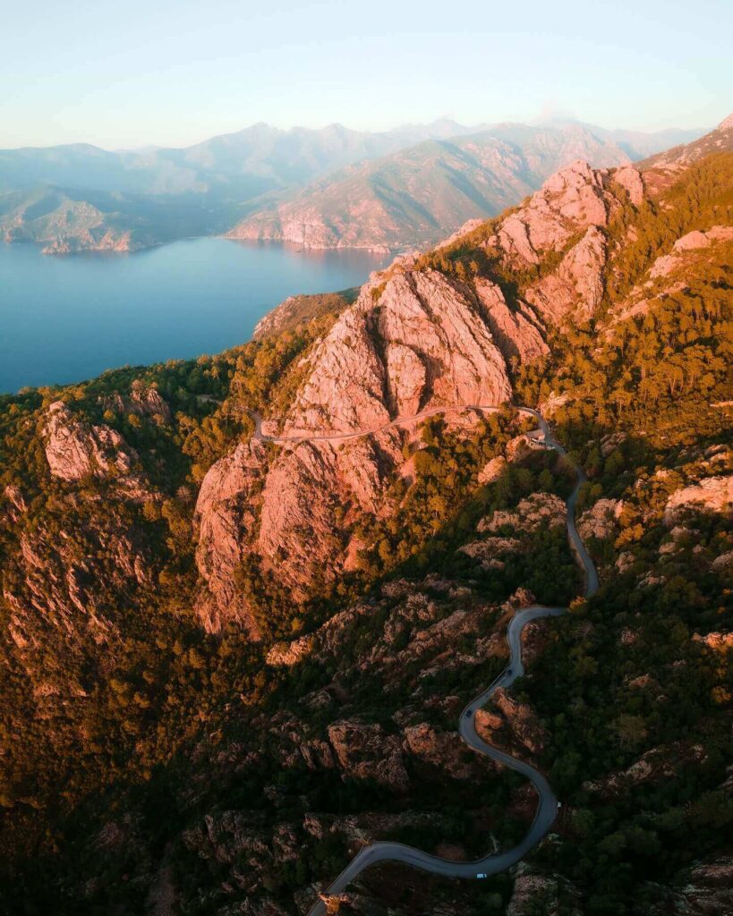 Car driving along the D81 road through the red granite cliffs of the Calanques de Piana