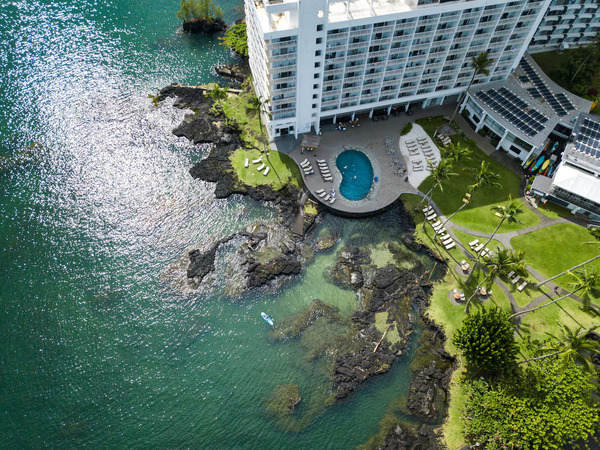 Exterior view of the Grand Naniloa Hotel Hilo (DoubleTree by Hilton) overlooking Hilo Bay on Hawaii’s east side, featuring oceanfront accommodations, tropical surroundings, and scenic coastal views, recognized as a top budget-friendly hotel option in Hilo.