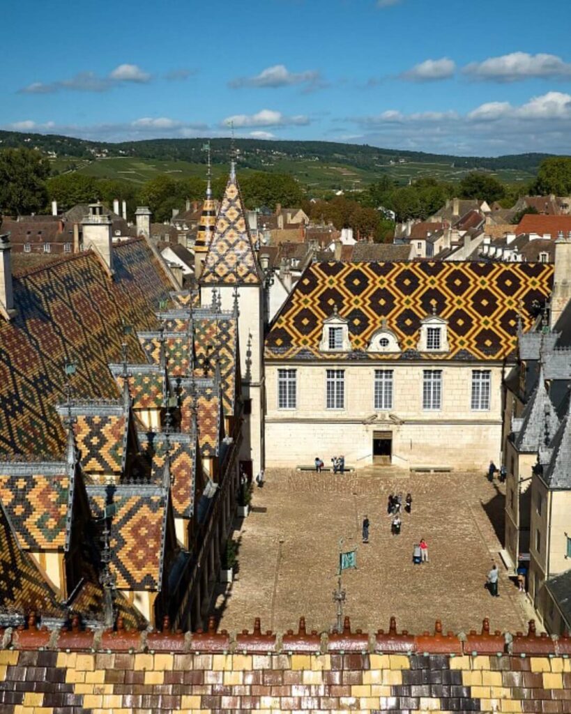 Courtyard and colorful tiled roofs of Hospices de Beaune in Beaune, France