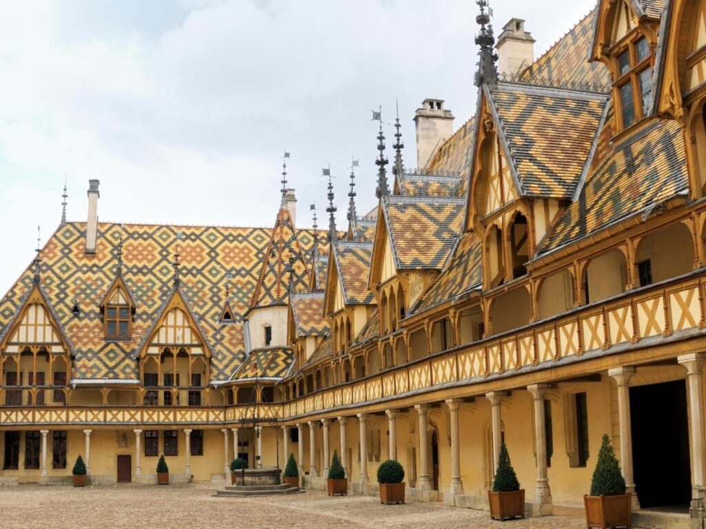 Historic courtyard of Hospices de Beaune surrounded by Gothic architecture and colorful roof tiles