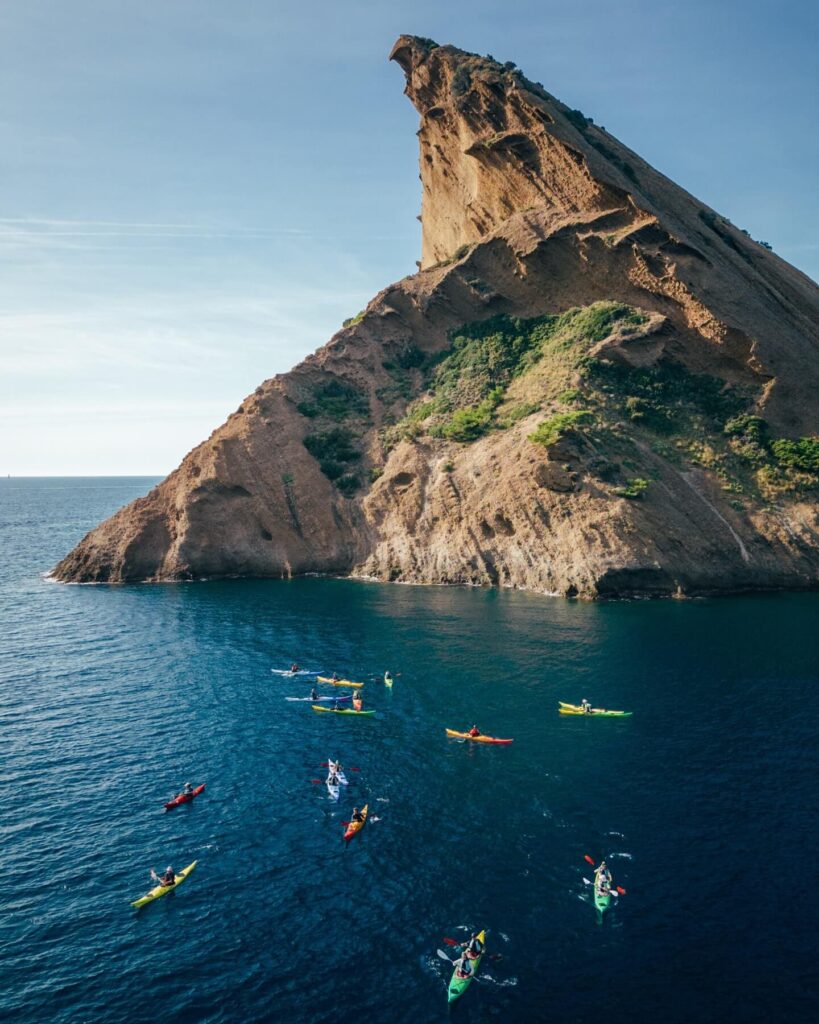 Kayakers exploring a calanque surrounded by limestone cliffs