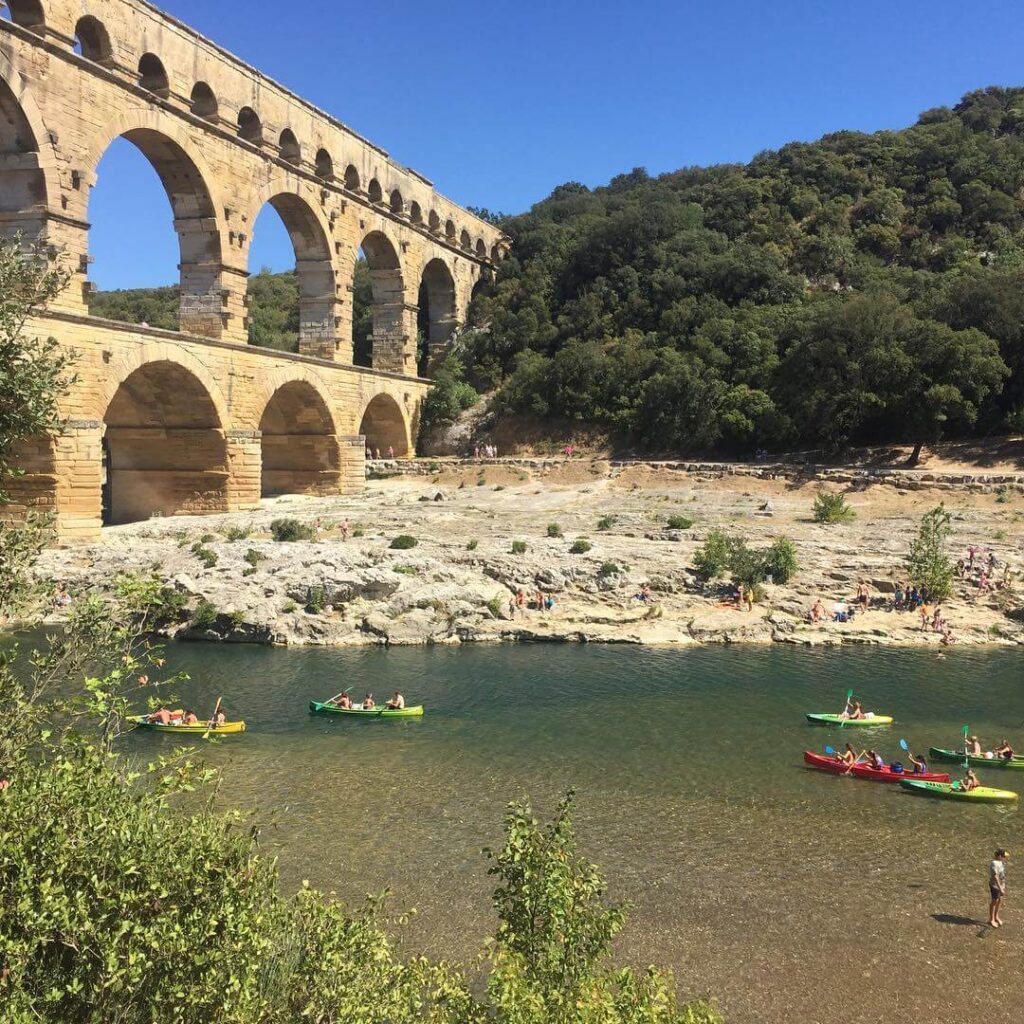 Kayakers paddling beneath the arches of Pont du Gard on the Gardon River