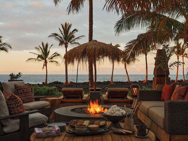 Romantic beachfront setting at Kona Village, A Rosewood Resort on Hawaii’s Big Island, featuring luxurious oceanfront hale-style accommodations, swaying palm trees, white-sand shoreline, and a stunning sunset atmosphere ideal for couples and honeymooners.
