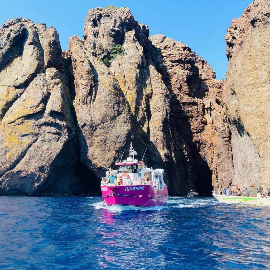 Large sightseeing boat cruising past the cliffs of Scandola Nature Reserve