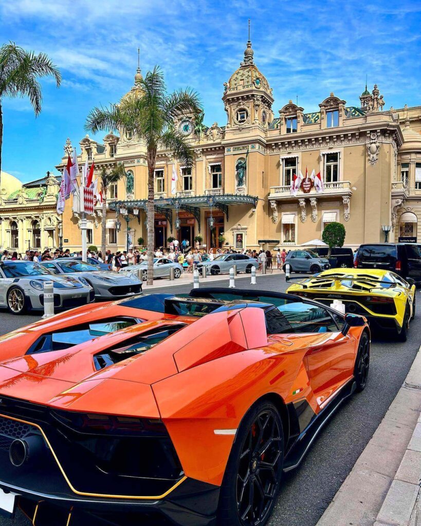 Monte Carlo Casino illuminated at dusk with luxury cars in Casino Square
