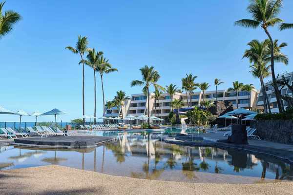 Panoramic oceanfront view of Outrigger Kona Resort & Spa on Hawaii's Big Island, featuring cliffside coastal scenery, tropical gardens, resort pools, and breathtaking Pacific Ocean sunsets.