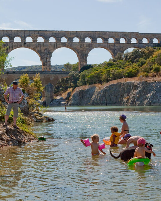 Visitors swimming beneath Pont du Gard during summer