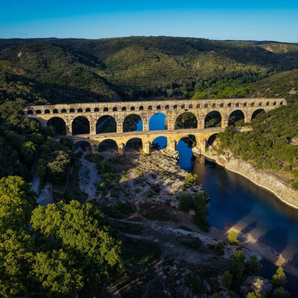 Three-tier Roman aqueduct design of Pont du Gard viewed from the riverbank