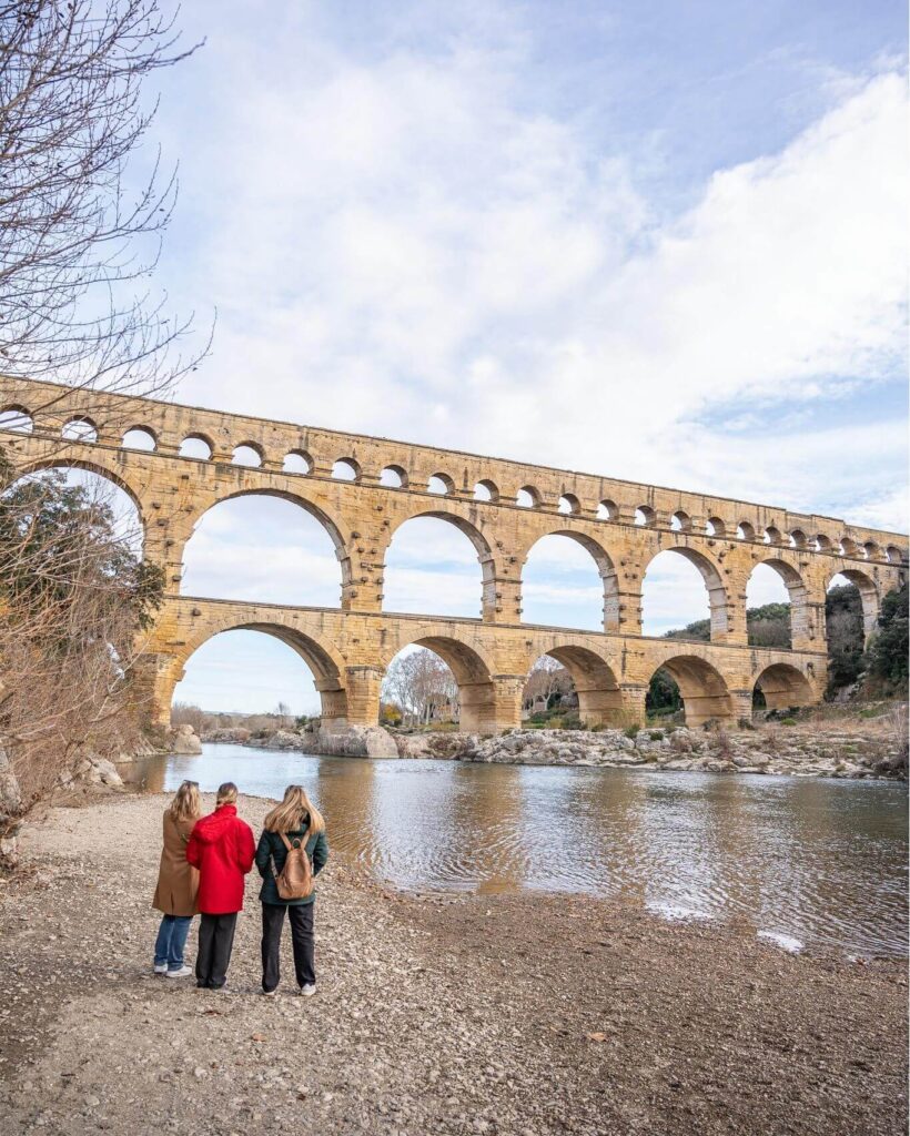 Visitor standing beneath the towering arches of Pont du Gard