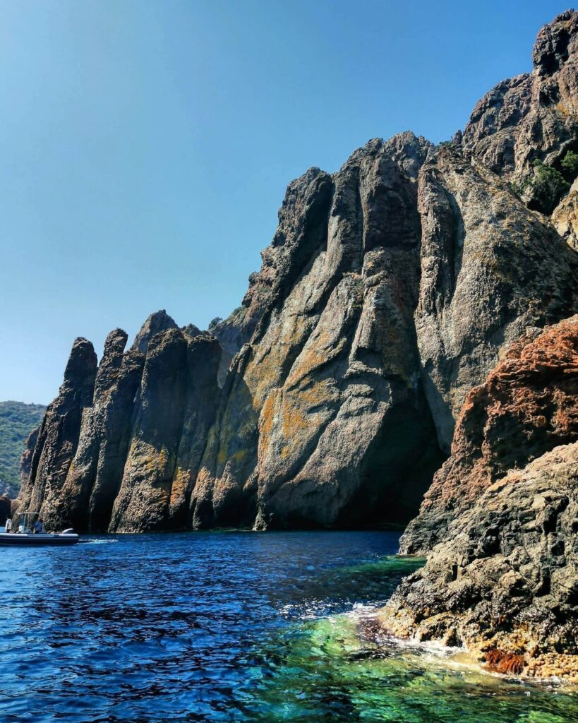 Boat entering a sea cave along the coastline of Scandola Nature Reserve