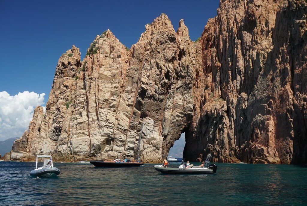 Visitors swimming in clear turquoise water near Scandola Nature Reserve