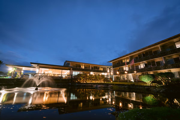 Relaxed waterfront view of SCP Hilo Hotel on Hawaii's Big Island, featuring modern eco-conscious accommodations, tropical landscaping, comfortable outdoor spaces, and a laid-back Hawaiian atmosphere.