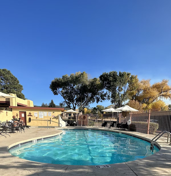 Exterior view of El Pueblo Lodge featuring traditional adobe-style architecture and beautifully landscaped grounds in Taos.