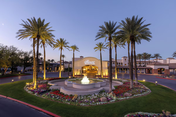 Sunset view of Fairmont Scottsdale Princess with palm trees and the Sonoran Desert landscape