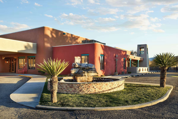 Welcoming entrance of Hotel Don Fernando de Taos, Tapestry Collection by Hilton with adobe-inspired design and landscaped grounds.