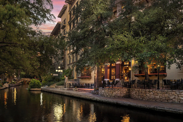Exterior view of Omni La Mansión del Rio on the San Antonio River Walk, showcasing Spanish Colonial-style architecture, lush courtyards, and an elegant riverside luxury hotel setting.