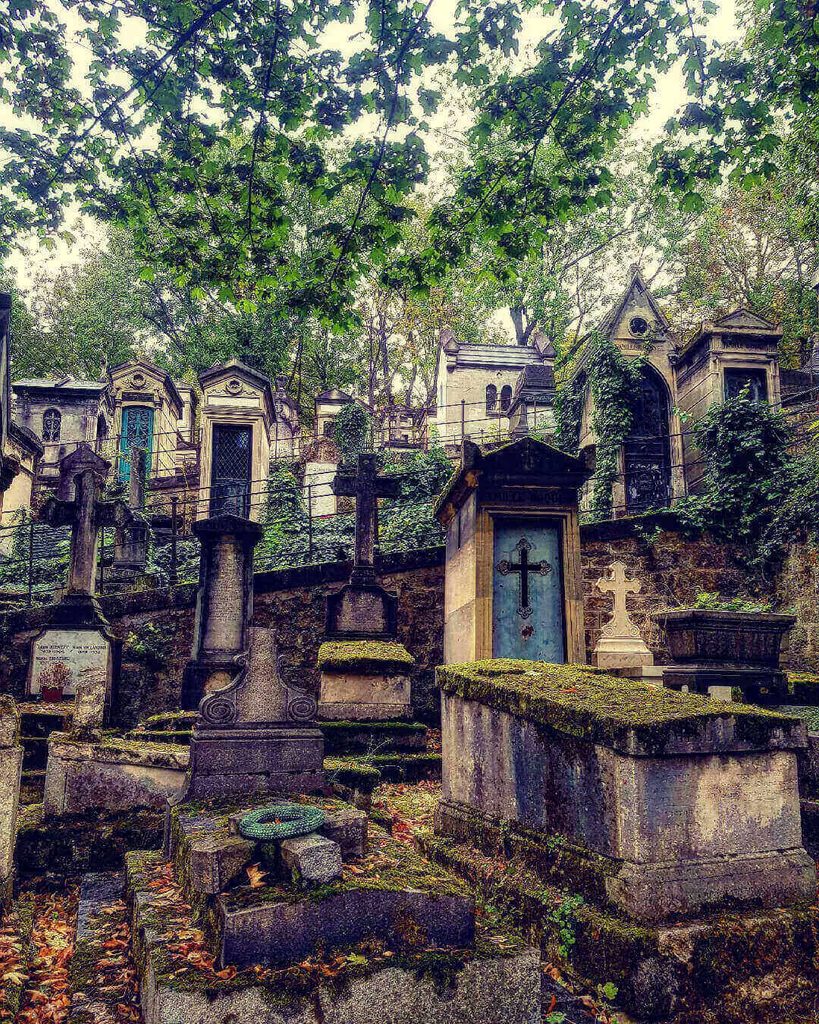 Quiet tree-lined path through Père Lachaise Cemetery in Paris