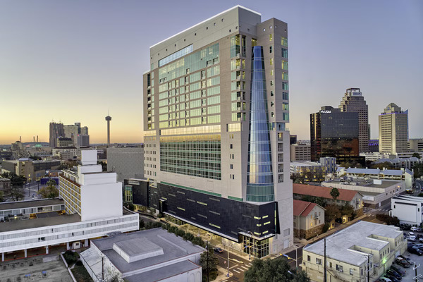 Exterior view of Thompson San Antonio Riverwalk, showcasing its modern high-rise architecture, stylish luxury design, and prime location overlooking the San Antonio River Walk.