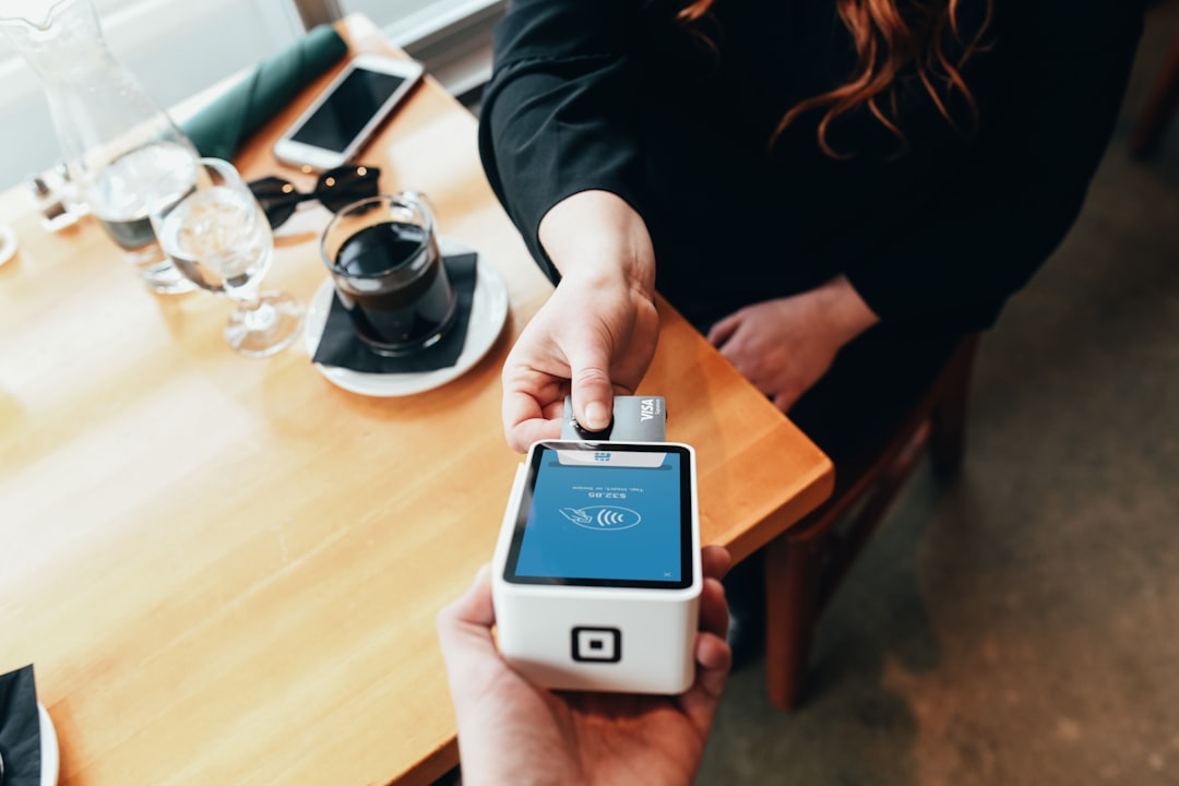 A hand holding a portable card payment terminal in a shop.