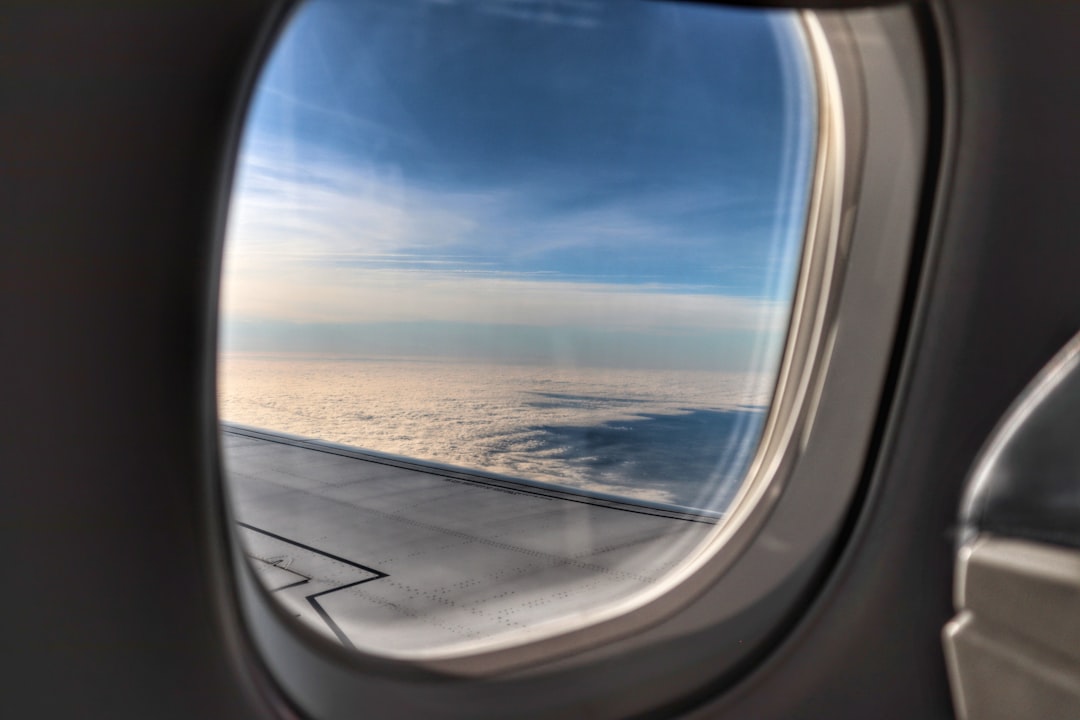 View of an airplane wing and clouds from a passenger window seat