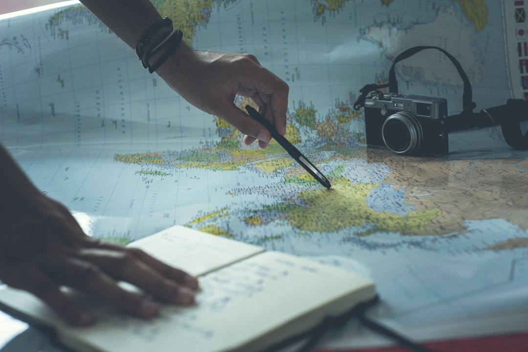 Traveler planning a trip with a notebook, map and laptop