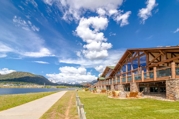 Scenic exterior view of The Estes Park Resort in Estes Park, Colorado, featuring its lakeside setting, mountain-inspired architecture, and beautiful Rocky Mountain surroundings.