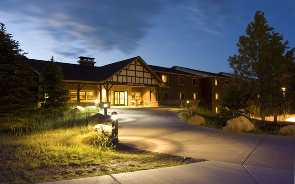Scenic view of YMCA of the Rockies in Estes Park, Colorado, featuring rustic lodge-style buildings surrounded by pine forests and the majestic Rocky Mountains.