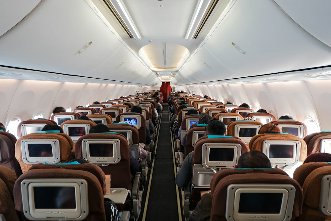 Rows of economy seats with seatback screens inside an airplane cabin