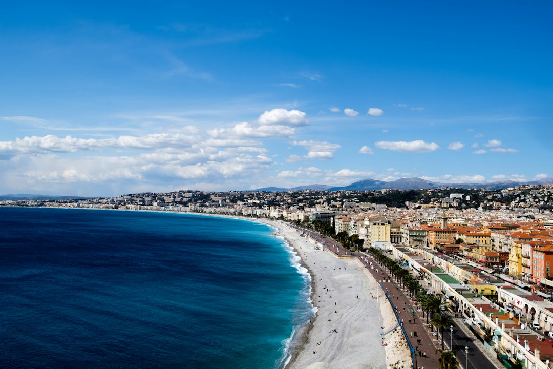 Aerial view of the pebble beach, blue sea, and seafront promenade along the coast in Nice on the French Riviera.