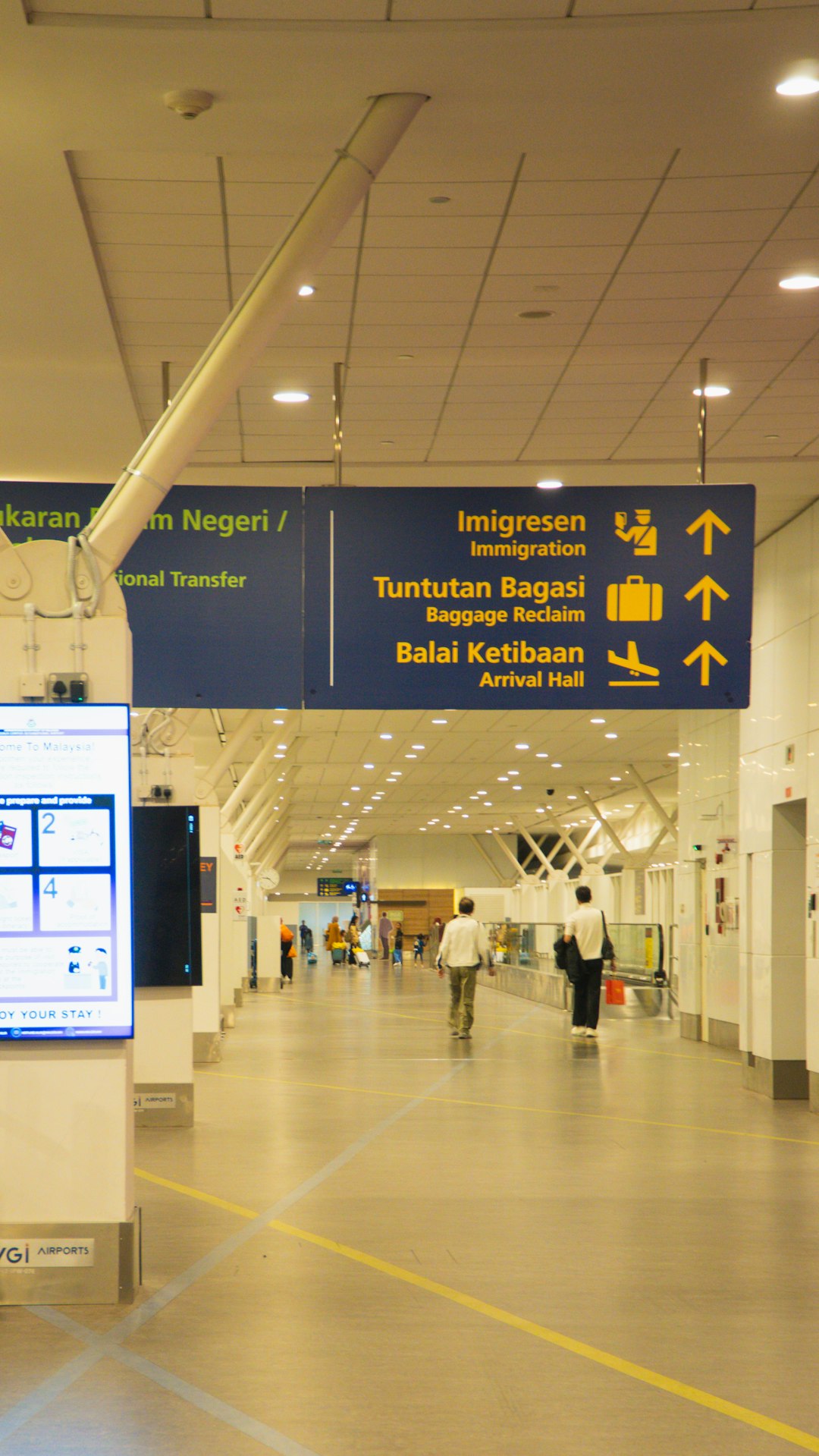 Bright airport hallway with directional signs toward immigration