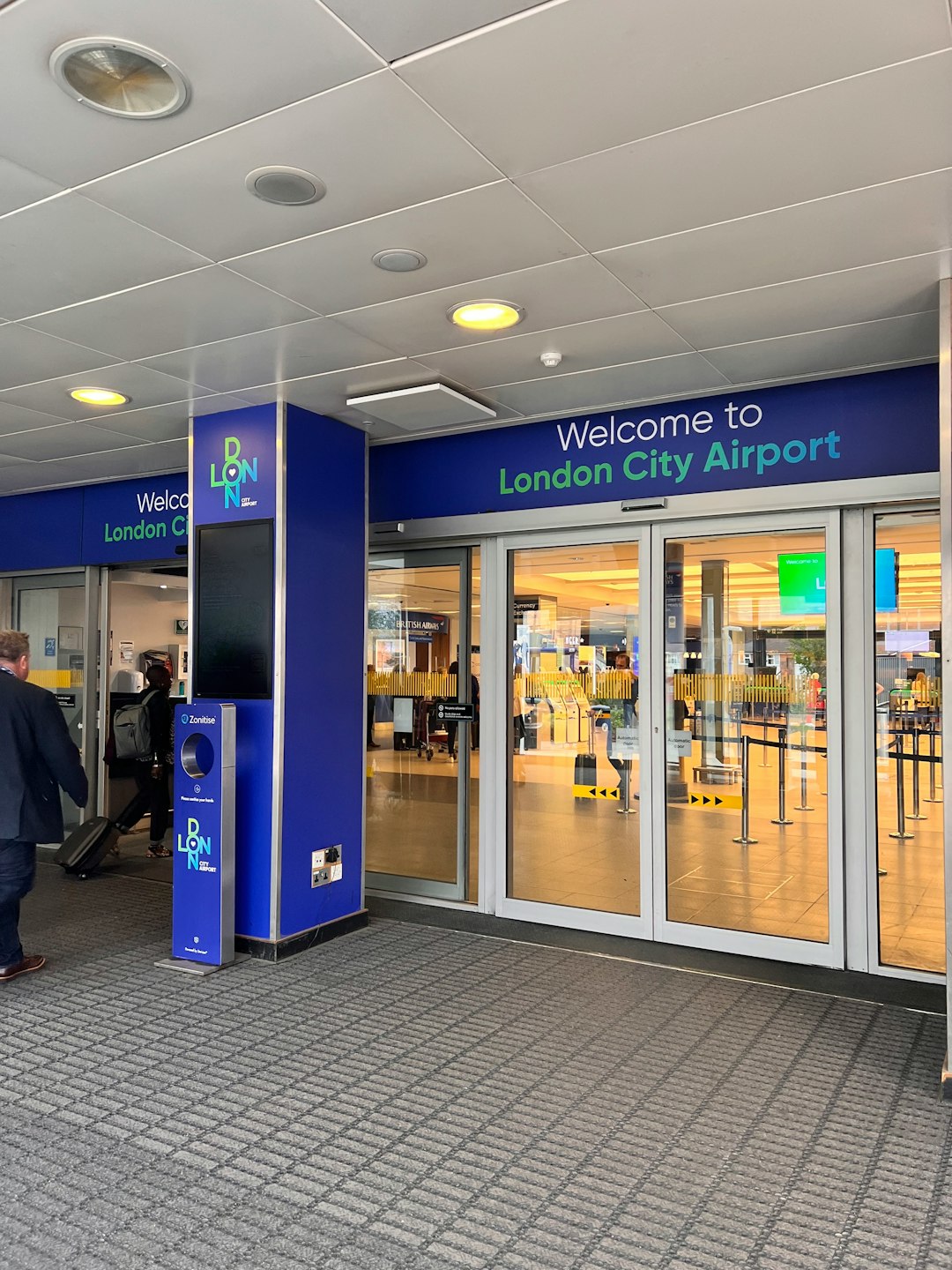 A traveler walking out of a London airport terminal with luggage