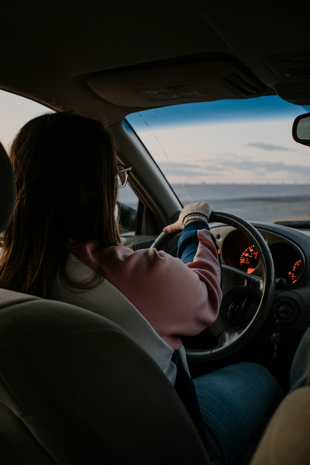 Woman in white long sleeve shirt driving car during daytime