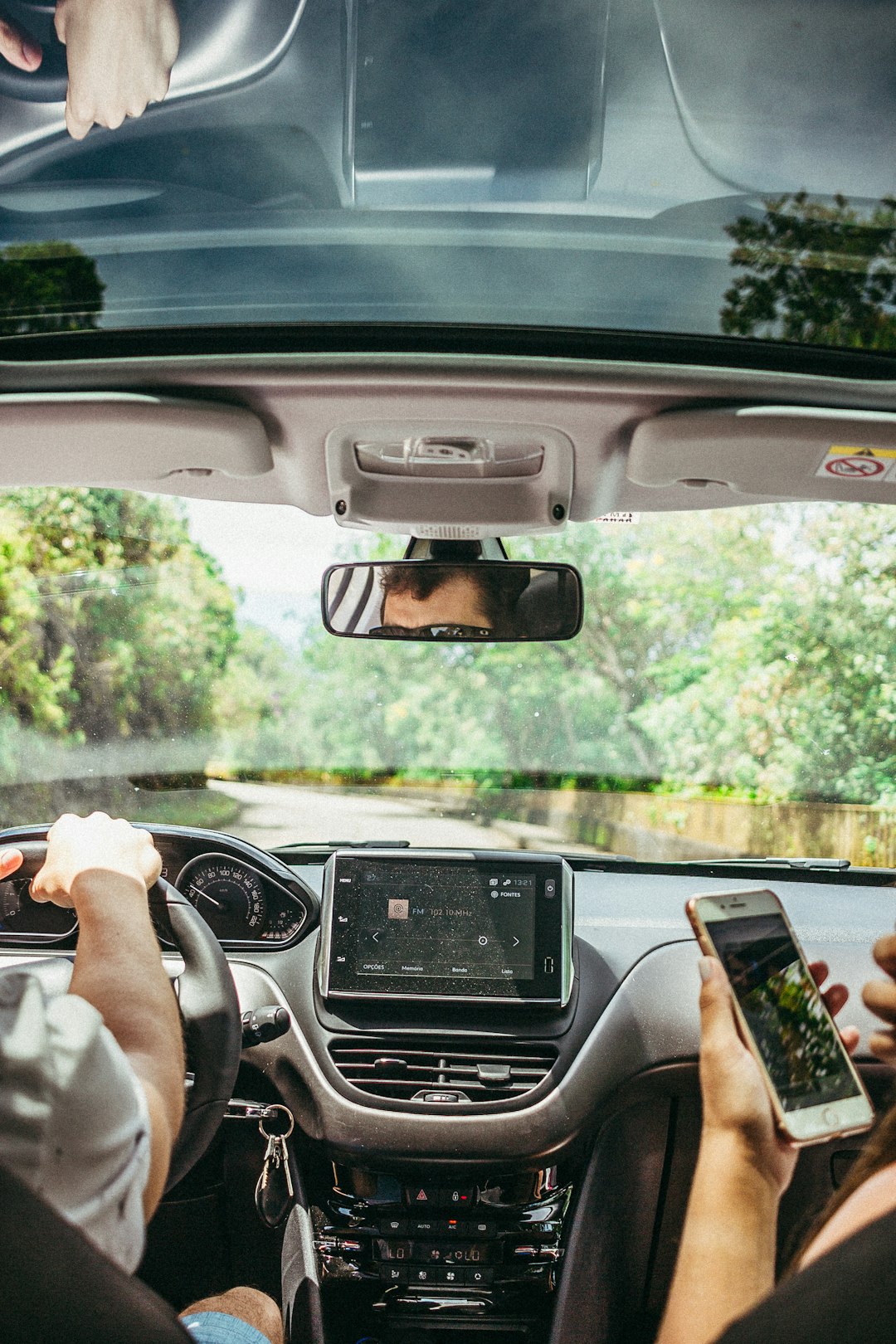 Man at the car seat holding his phone beside the driver