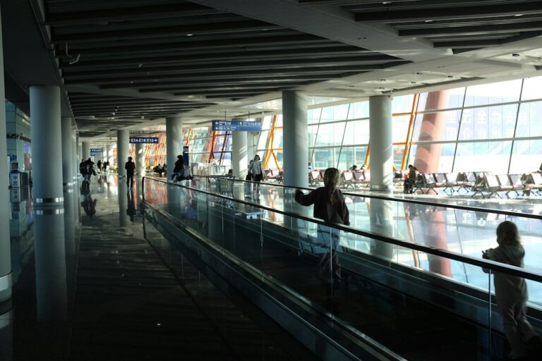 Travelers walking through a modern airport terminal toward departure gates