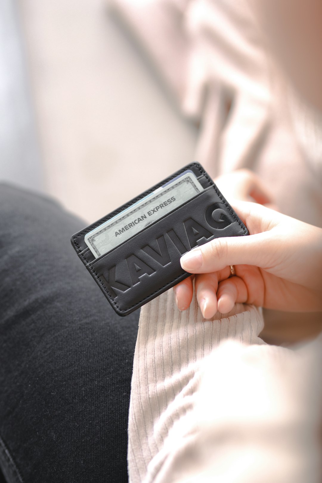 A leather cardholder wallet held in one hand