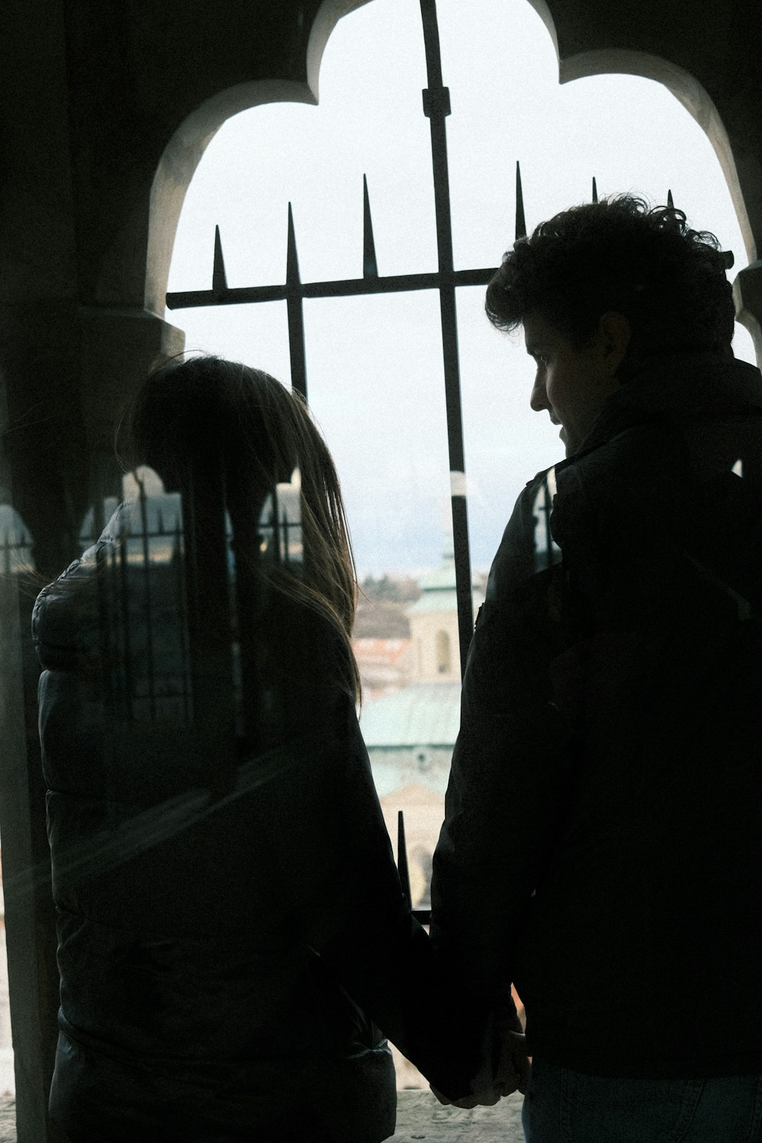 A couple holding hands while looking out a large window