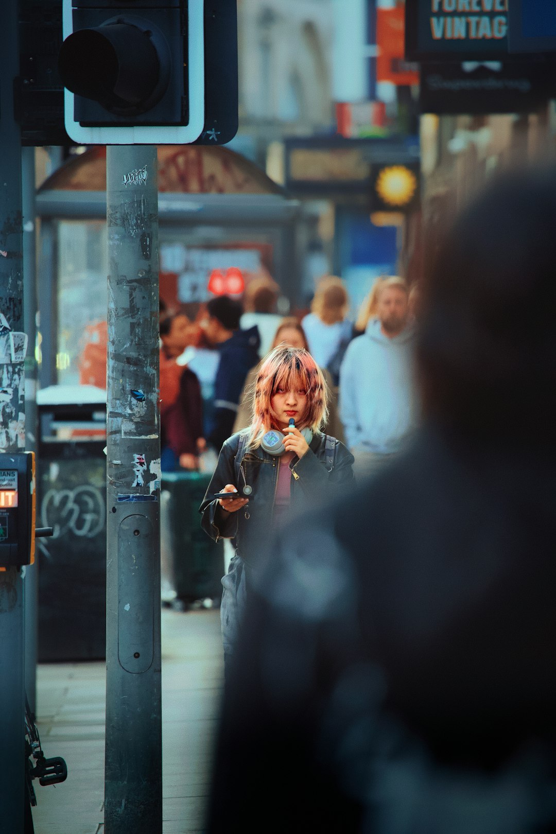 A young person holding a smartphone on a busy city street