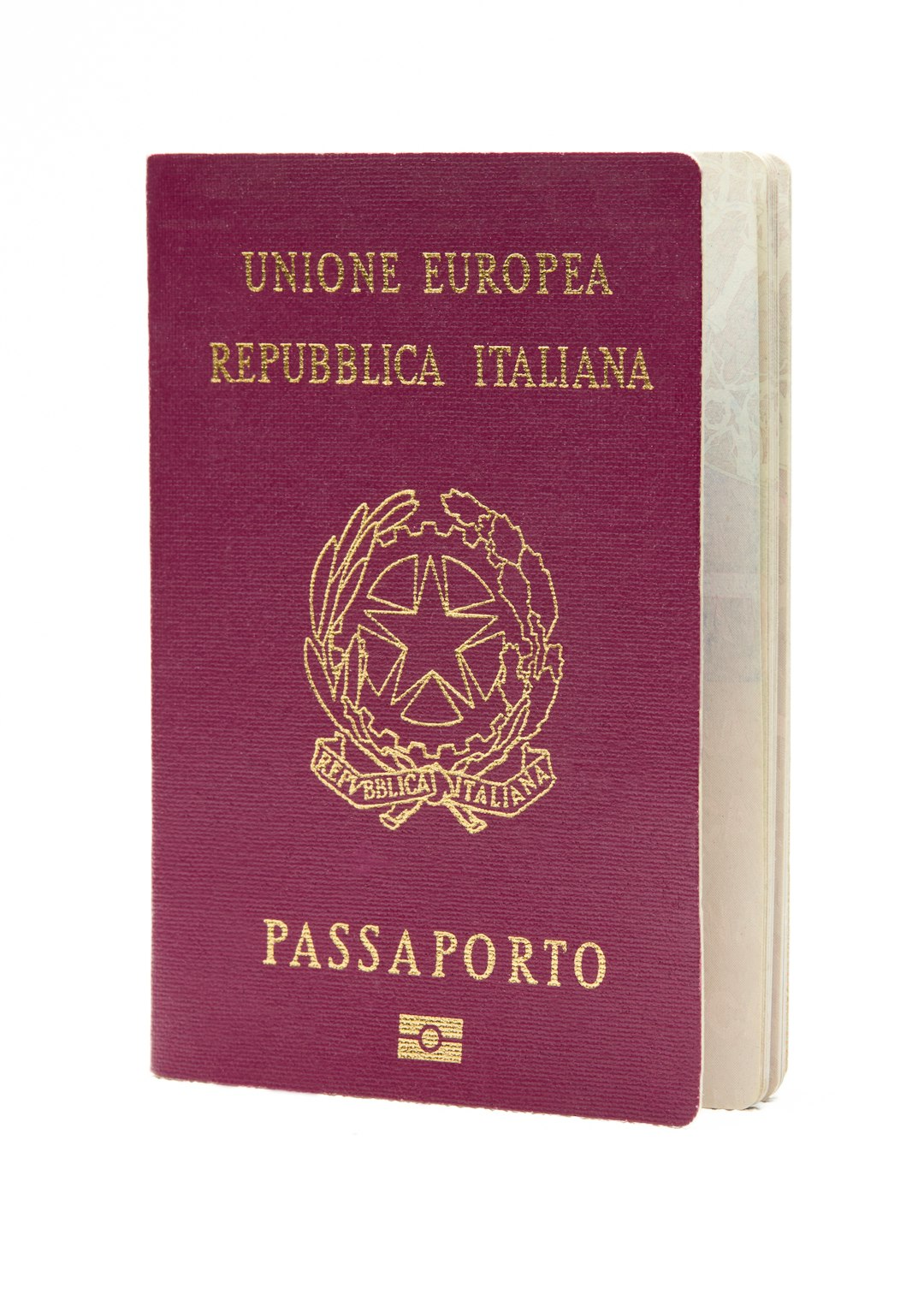 The image shows an Italian passport standing upright against a white background. The passport has a burgundy cover wi...